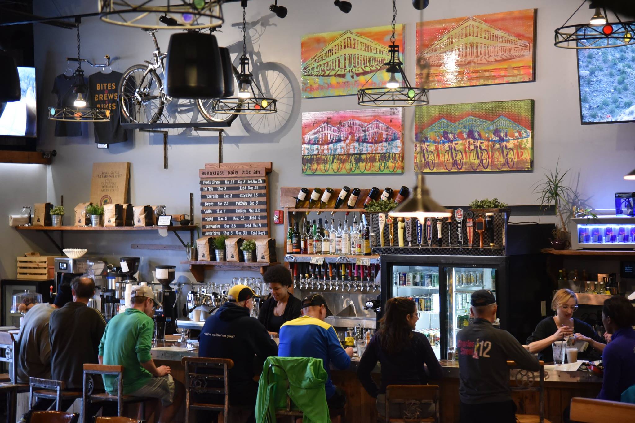 The HandleBar Café and Bike Shop is decorated with bike-themed art, the hand made bar stools and bar top feature bike components, and the bar taps have mountain bike grips for handles. Bikes are displayed throughout the space.