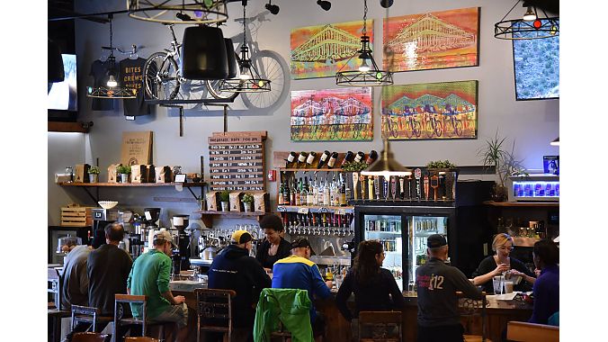 The HandleBar Café and Bike Shop is decorated with bike-themed art, the hand made bar stools and bar top feature bike components, and the bar taps have mountain bike grips for handles. Bikes are displayed throughout the space.