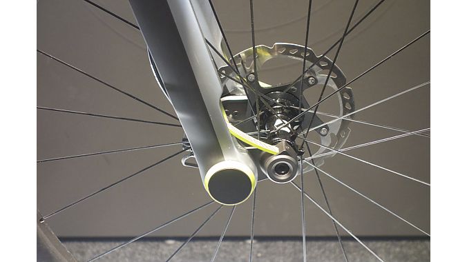 The front axle pivots around a bearing, allowing up to 15 mm of travel. The neon yellow part is the carbon swing arm. The pivot bearings provide electronically controlled damping.