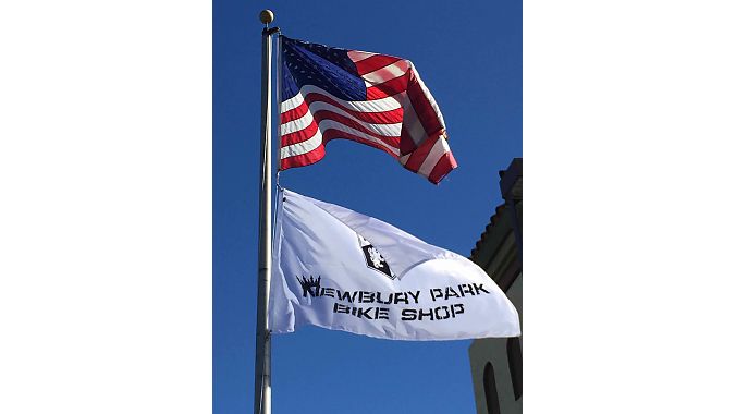The flagpole from the former post office Newbury Park Bicycle Shop moved into last spring is grandfathered into the building's lease, allowing the shop to fly its banner alongside the Stars and Stripes.